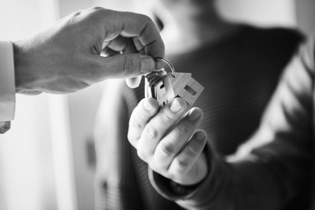 hombre entregando llaves de casa a otro hombre en blanco y negro