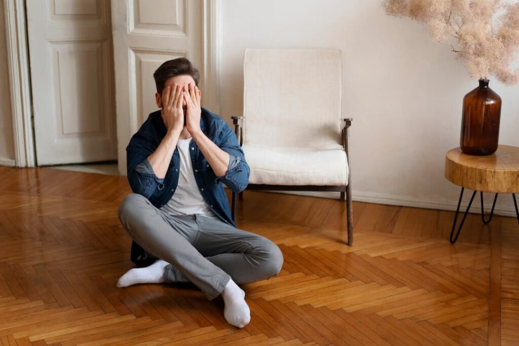 hombre sentado en el piso con manos en el rostro